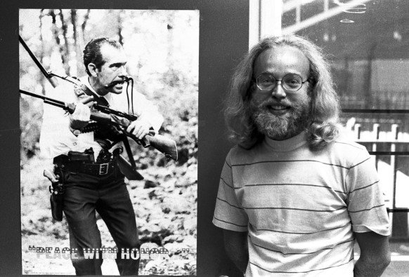 Paul Martin, smiling and standing next to a poster